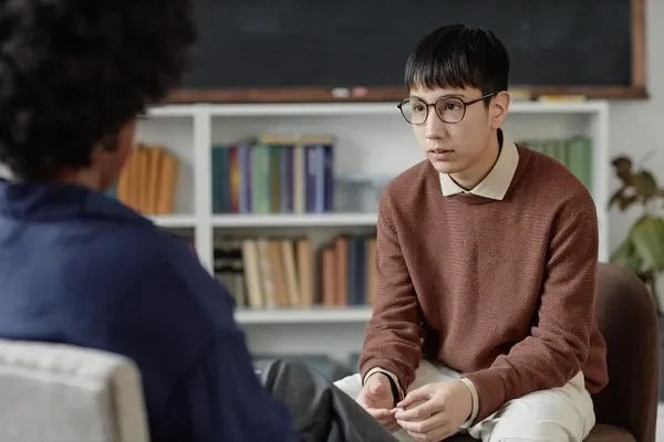 Un consejero y un estudiante participan en una sesión de actividades de orientación vocacional en una sala llena de libros