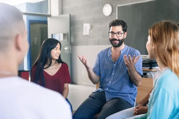 Profesor explicando un tema a estudiantes diversos en un aula durante cursos vocacionales.