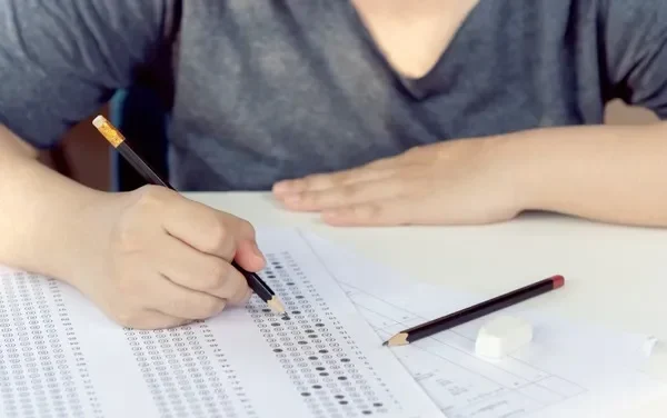 Un primer plano de un estudiante que completa un examen como parte de las actividades de orientación vocacional, con un lápiz en la mano.